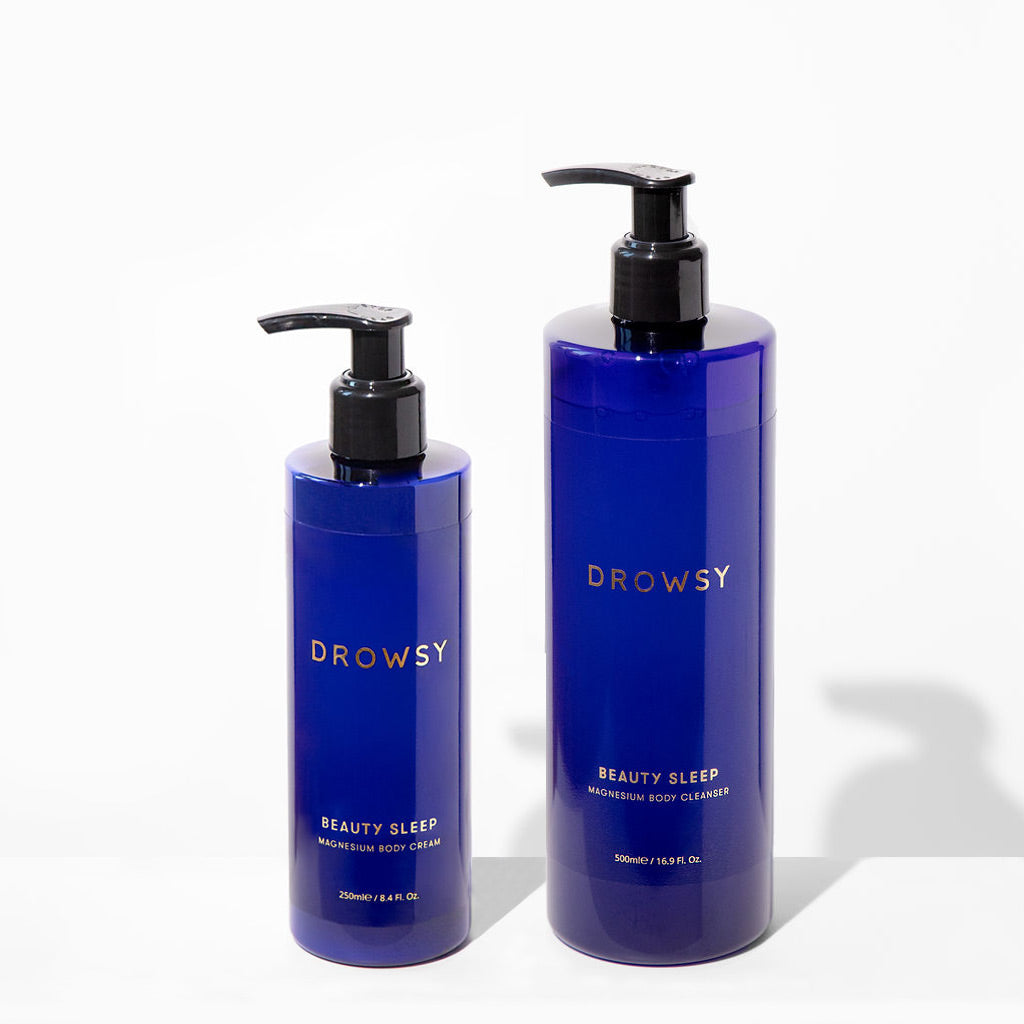 Two blue pump bottles from us.drowsysleepco’s Beauty Sleep Bundle stand side by side, offering magnesium-infused body care for restful beauty sleep—a smaller Body Cream and a larger item for your nighttime routine.