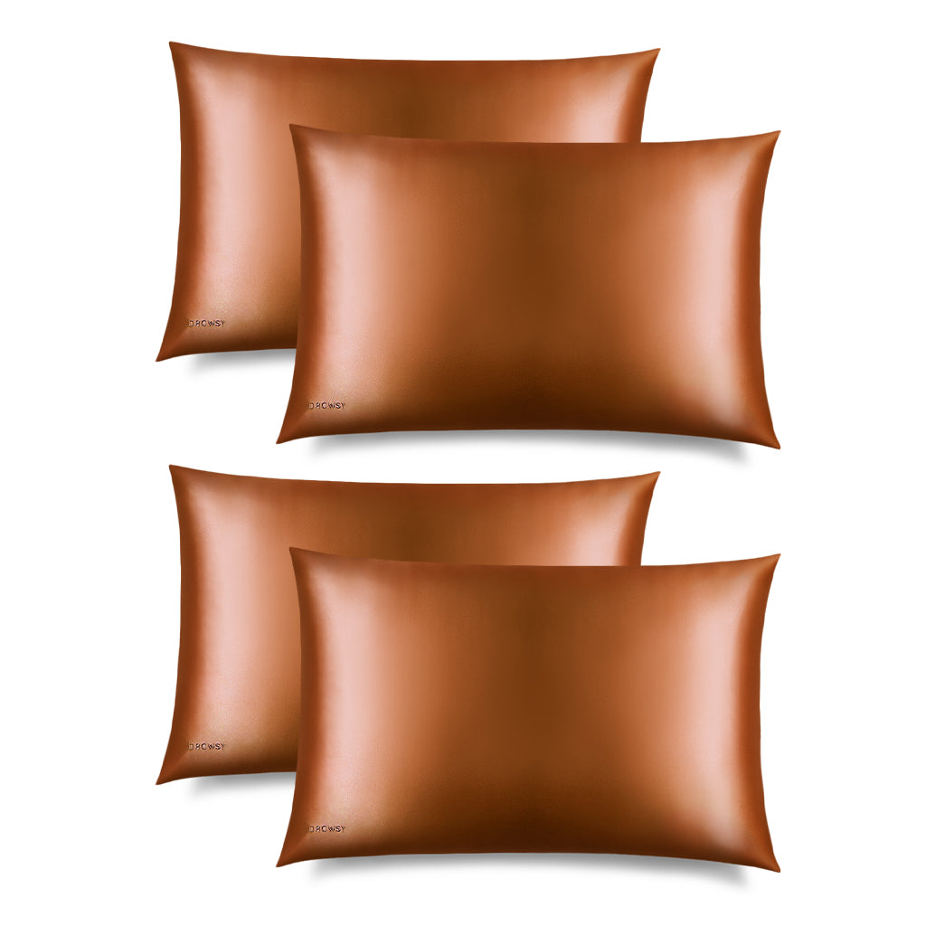 Set of four Pumpkin Spice Silk Pillowcases by us.drowsysleepco arranged in two rows on a white background. Each copper-colored pillowcase has a smooth, hair-protecting texture and features a small brand logo in the bottom corner.