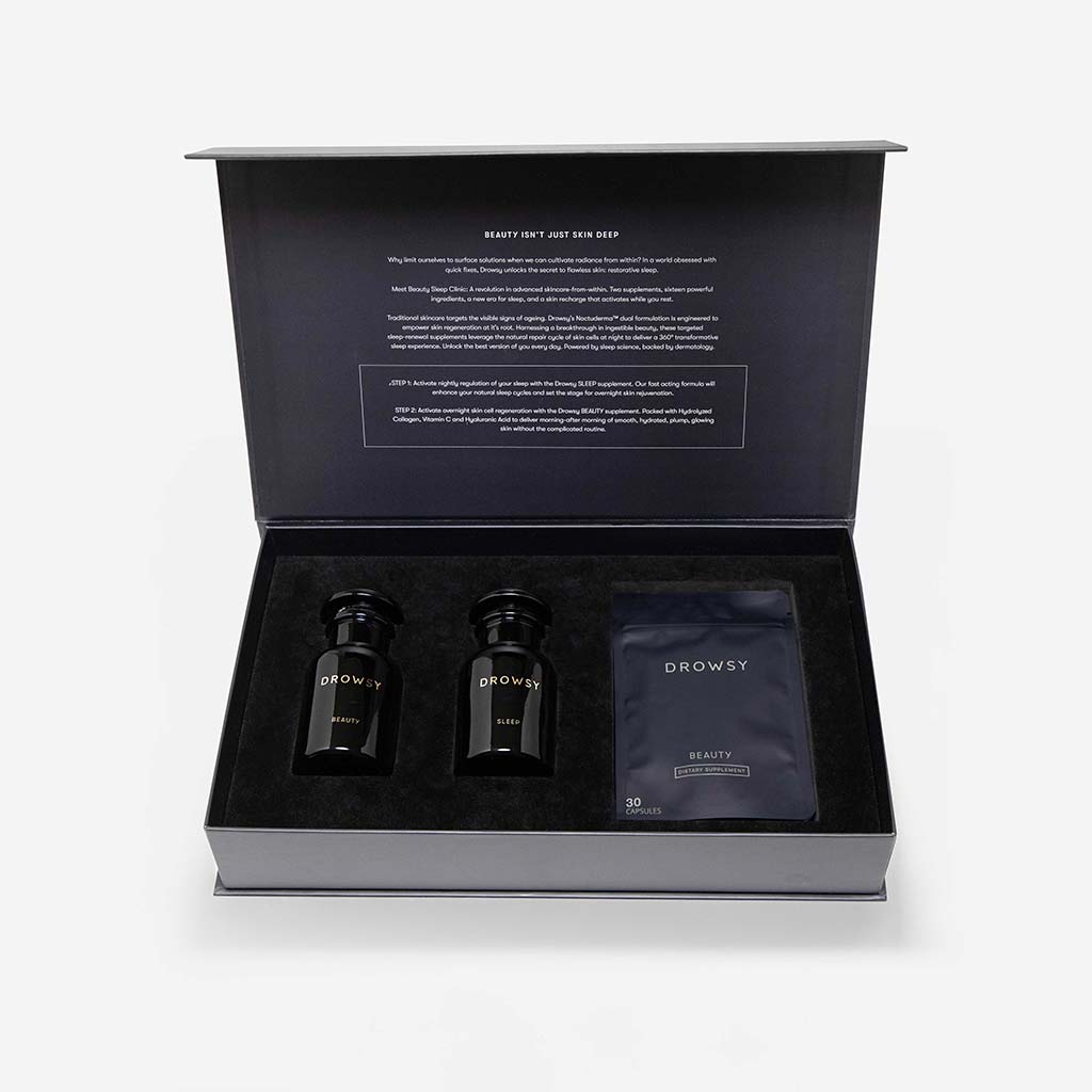 A black box set from us.drowsysleepco, labeled Supplements - Beauty Sleep Clinic, includes two black jars and a packet in a foam insert, with inside-lid info about its restorative sleep supplement.