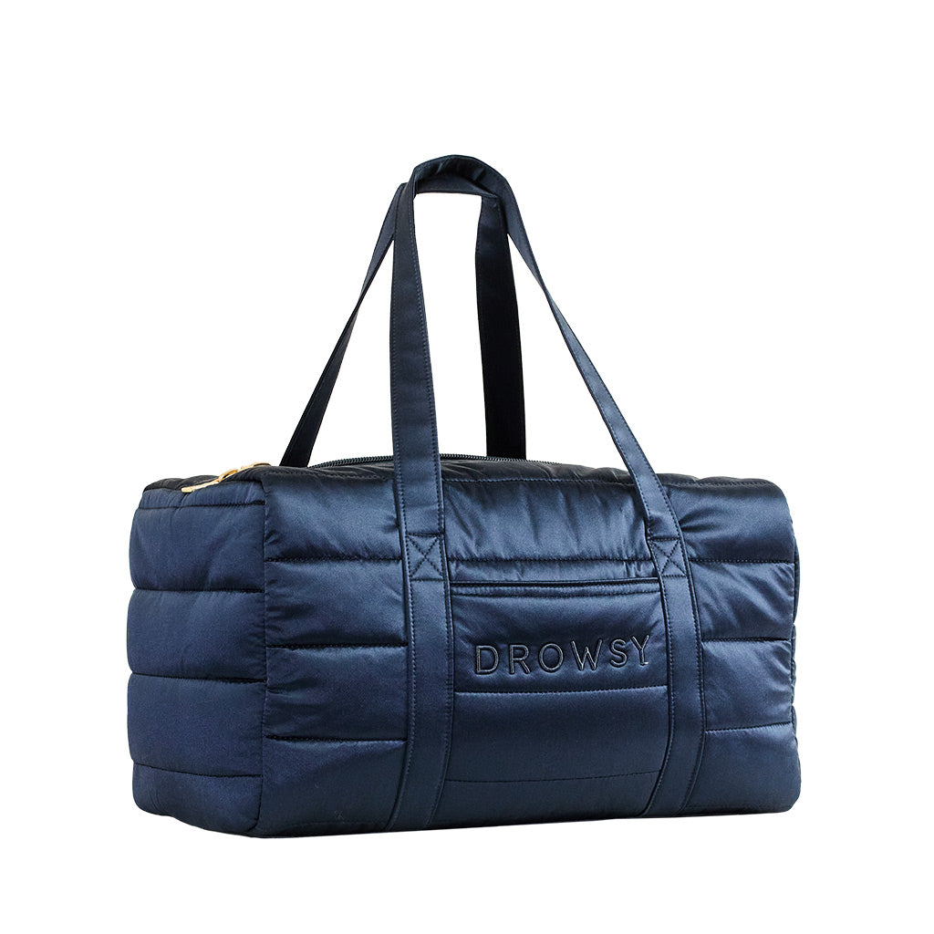 The Drowsy Silk Weekender - Midnight Blue is a quilted bag with double handles, gold zipper, and Drowsy branding—ideal for your travel essentials.