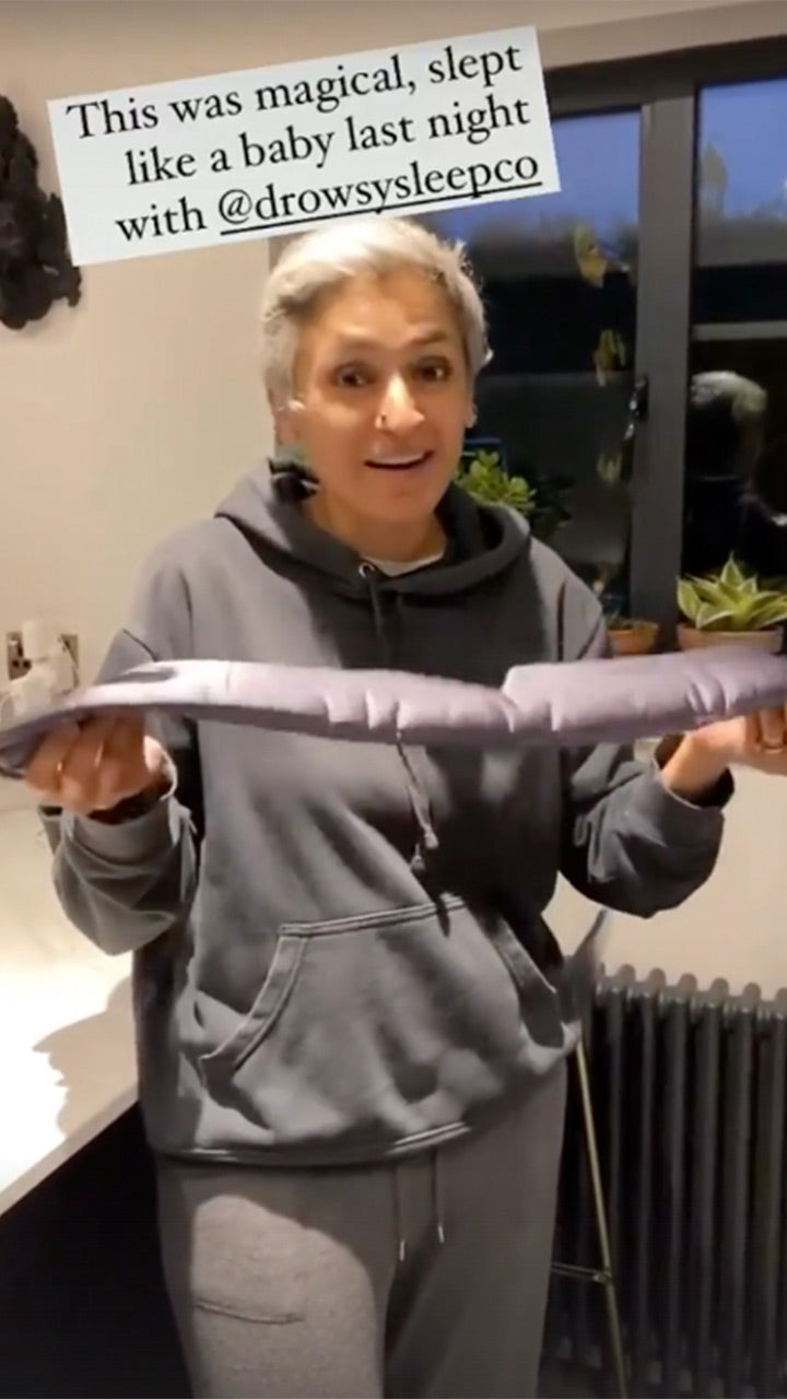 A person in a dark hoodie and sweatpants stands indoors, holding a long, cylindrical object. Text above reads: This was magical, slept like a baby last night with @drowsysleepco.
