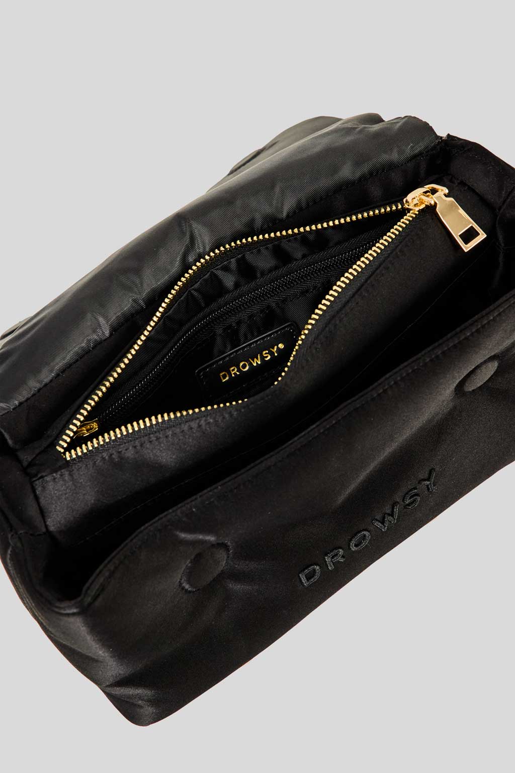 The Drowsy Silk Necessaire - Black Jade by Drowsy features a black satin-like finish, gold zipper, zippered inner pocket, and the Drowsy logo on both the lining and exterior—ideal for skincare or beauty essentials.