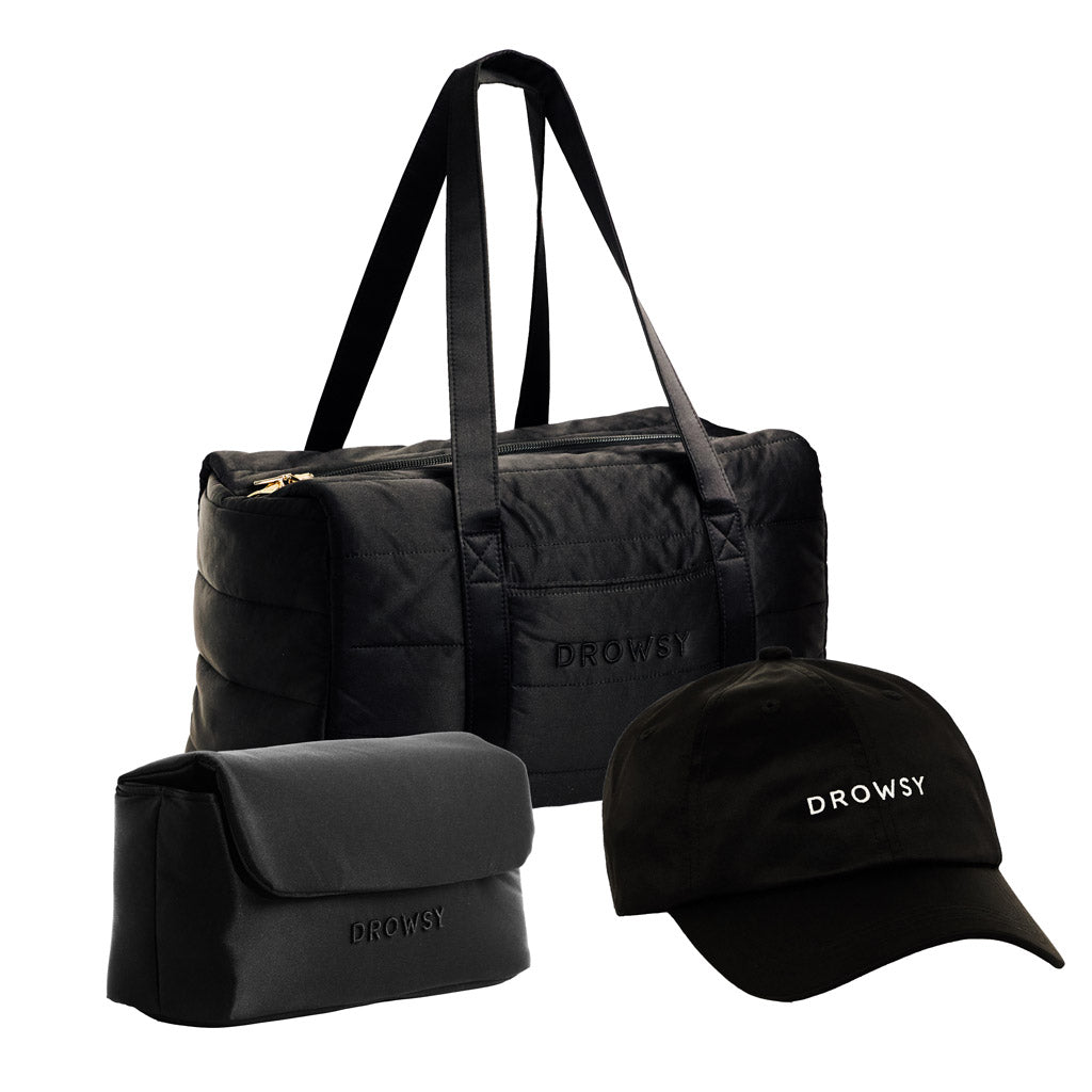 The Drowsy Weekend Collection - Black Jade features a black duffel, toiletry bag, and cap—all by Drowsy, with DROWSY embroidered in white on the duffel and cap—displayed on a white background.