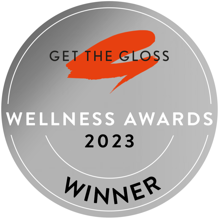A silver circular badge with GET THE GLOSS at the top, an orange brushstroke, WELLNESS AWARDS 2023 in the center, and WINNER at the bottom.
