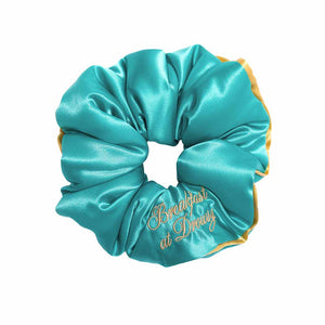 The Breakfast at Drowsy - Turquoise Padded Scrunchie by drowsysleepco is an oversized satin scrunchie with gold trim, designed for extra volume and embroidered with “Breakfast at Drowsy” in gold thread.