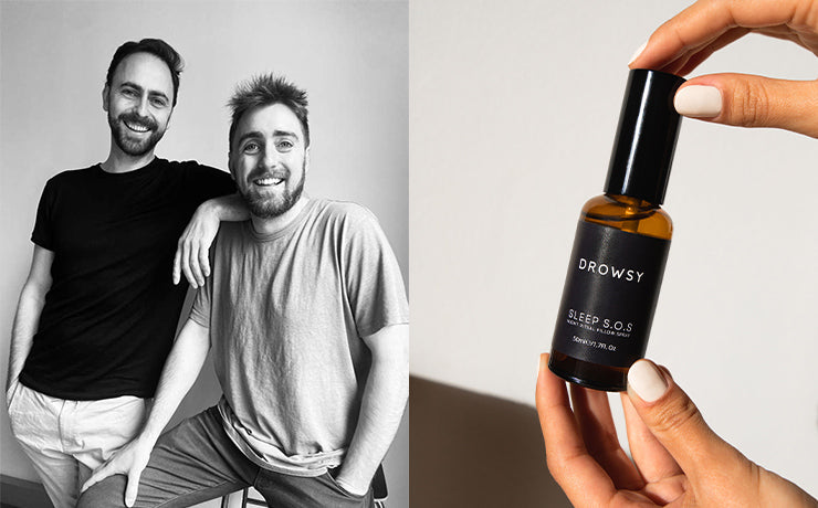 Two smiling men pose together on the left side of the image; on the right, hands hold a small amber bottle labeled Drowsy Sleep S.O.S. Recovery Pillow Oil.