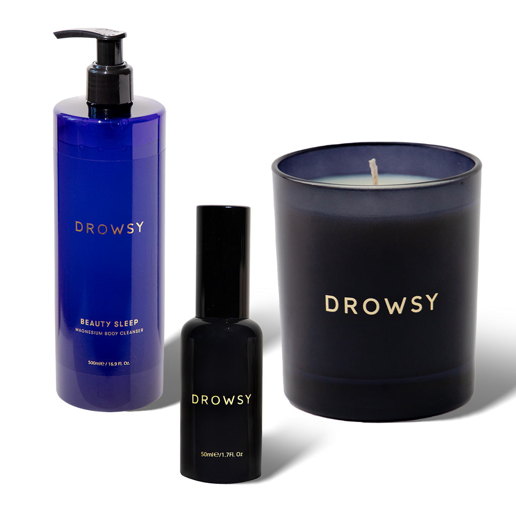 The drowsysleepco Wind-down bundle includes a tall blue Beauty Sleep Body Cleanser, a compact pillow spray, and a dark blue sleep candle in a glass holder—all featuring gold lettering on white.