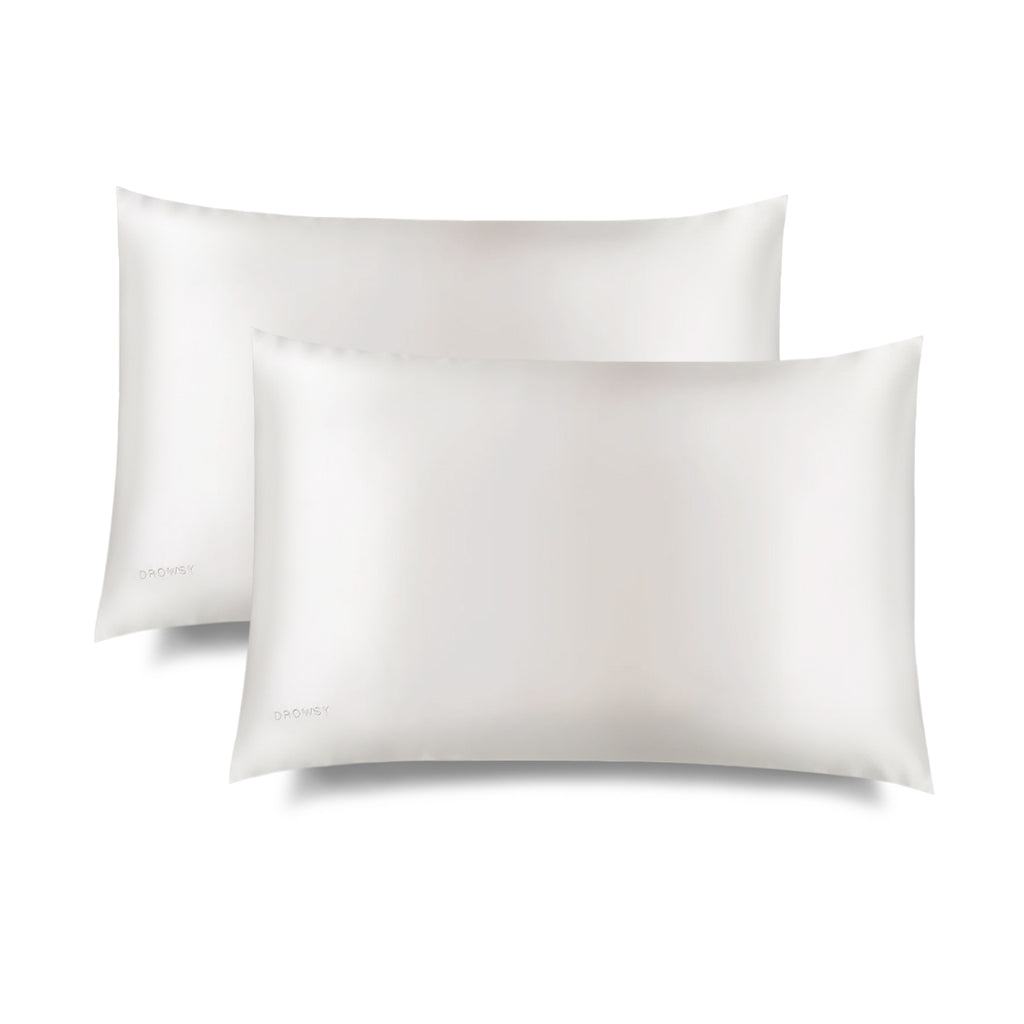 Two Akoya Pearl Silk Pillowcases by us.drowsysleepco, white and rectangular, are side by side on a white background. They offer hair protection and skincare benefits, with slight shadowing beneath them.