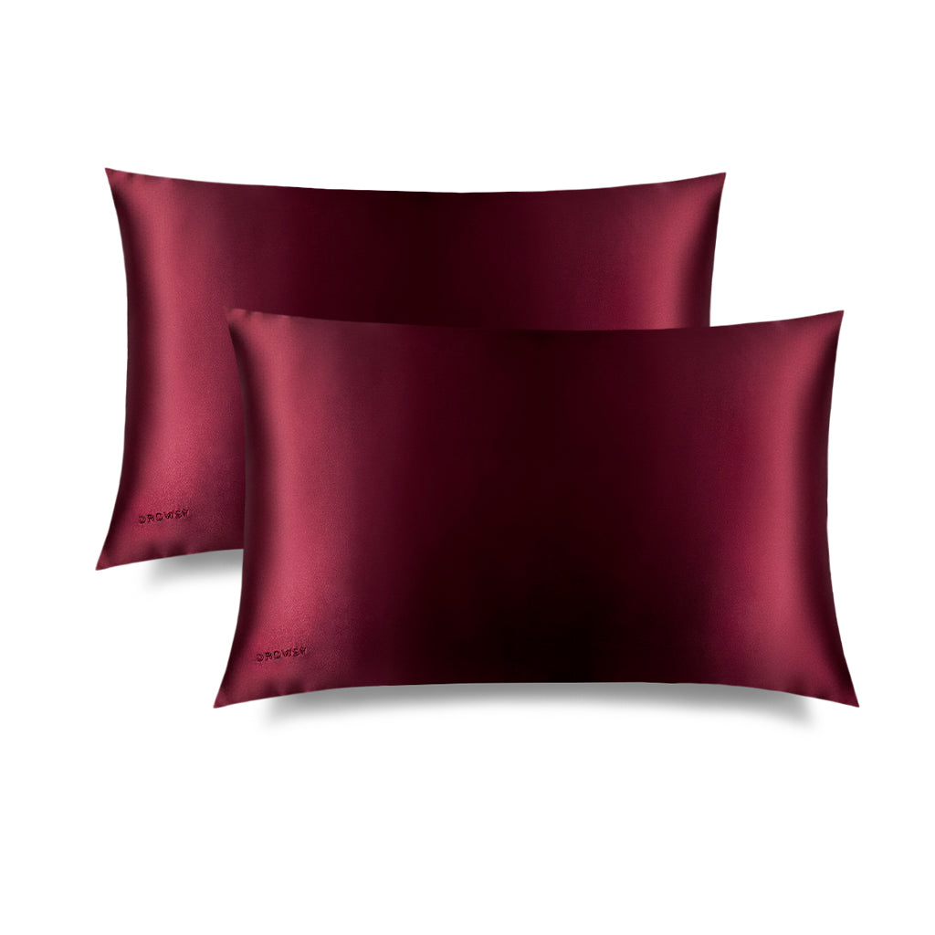 Two La Vie En Rouge Silk Pillowcases by us.drowsysleepco are shown overlapping on a white background, each with an embroidered logo—an elegant skincare essential and hair protector for your nightly routine.