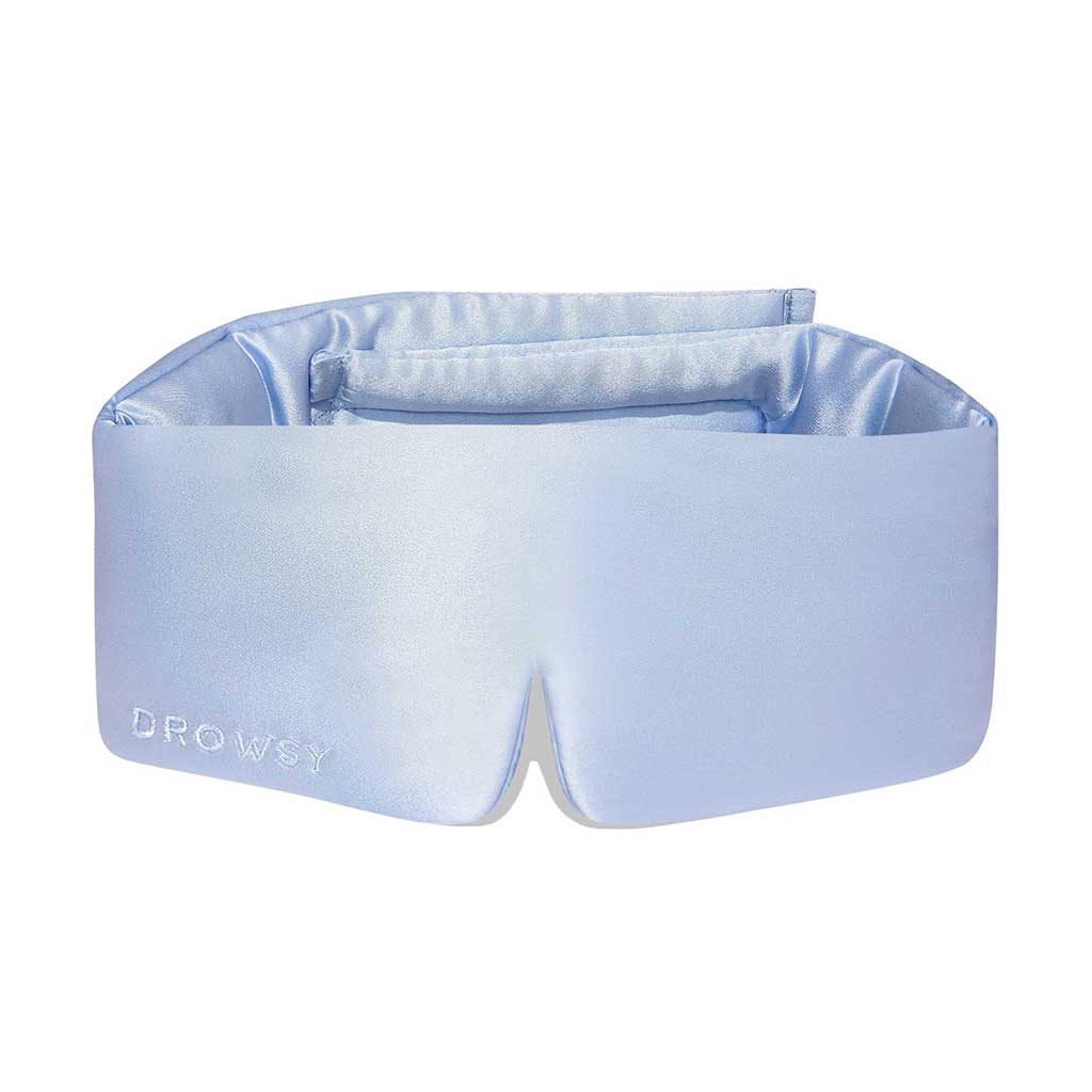 The Blue Belle silk eye mask by us.drowsysleepco features DROWSY embroidered on the left side. Designed to enhance beauty sleep, it comes in light blue and is shown against a white background.