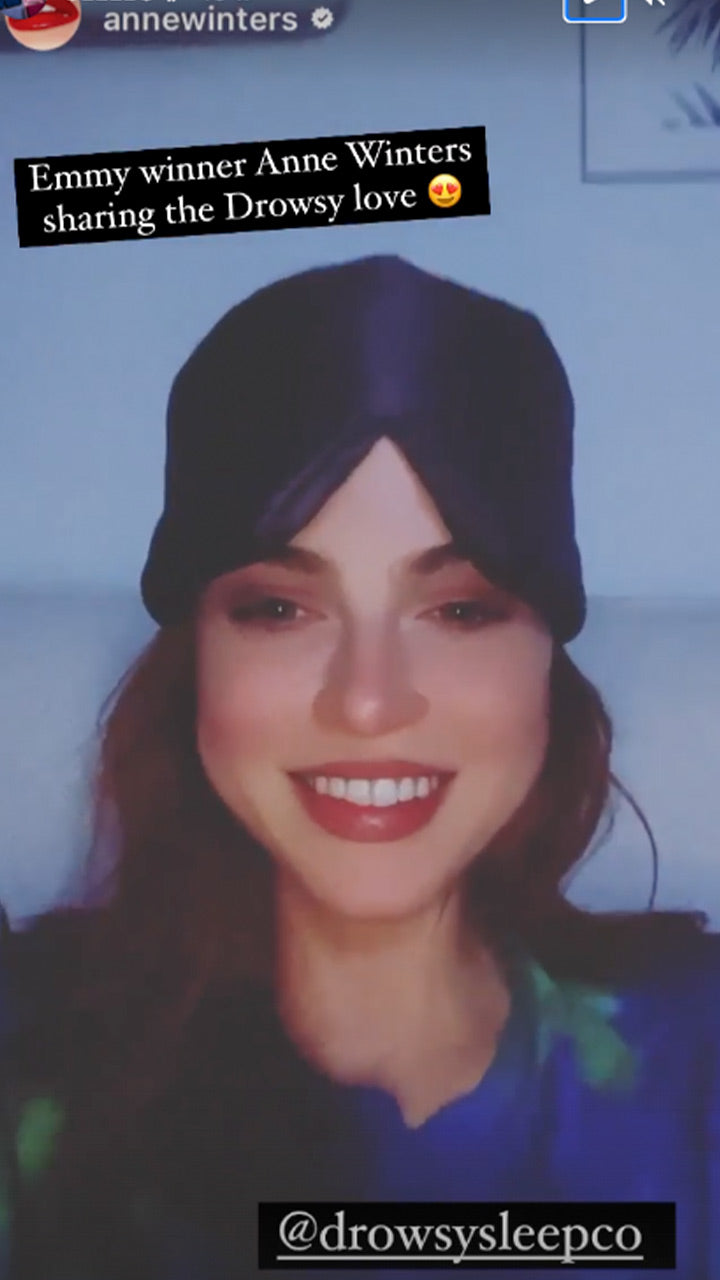 A woman with long hair smiles while wearing a black sleep turban. Text on the image reads, Emmy winner Anne Winters sharing the Drowsy love 😍 and @drowsysleepco.