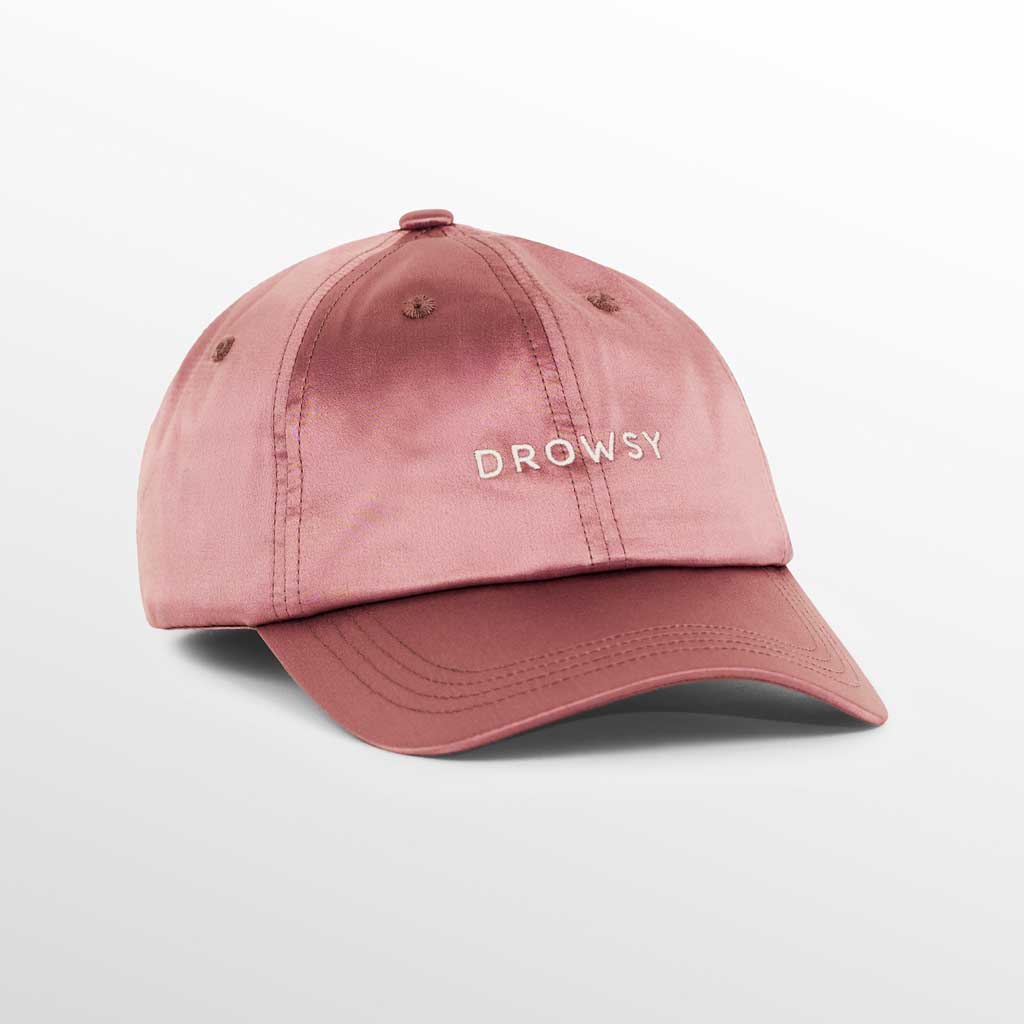 The Drowsy Silk Cap - Damask Rose by Drowsy features DROWSY embroidered in white on a pink silk cap, ideal for outdoor workouts and keeping your hair flawless. Displayed on a plain white background.
