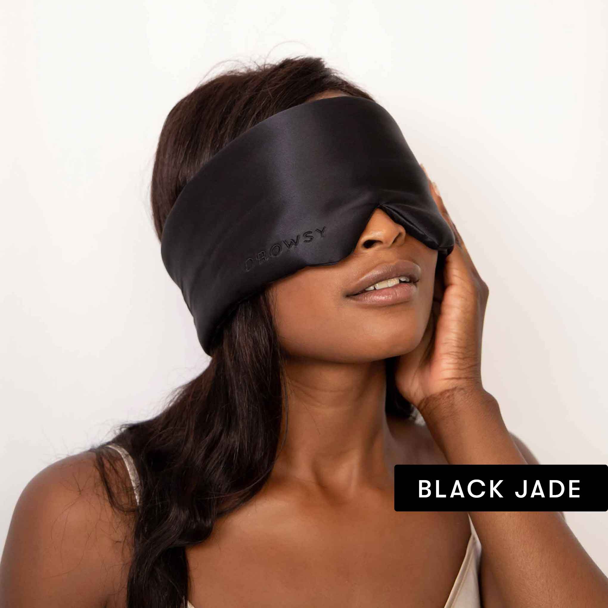A woman with long dark hair wears a large silk mask and gently touches her face. The words “Drowsy Lovers Pack” appear in the bottom right corner, highlighting the ultimate beauty sleep experience.