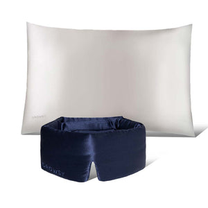 The Perfect Skin Bundle Midnight Blue by drowsysleepco features a white silk pillowcase and a navy blue padded sleep mask, displayed on a white background with the mask in front of the pillow for the ultimate beauty sleep.