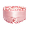 A person with wavy hair lies on a pink satin pillow, wearing drowsysleepco’s Sleep and the City Powder Pink mulberry silk blackout sleep mask, and a pink satin top, appearing relaxed and comfortable.
