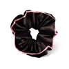 A woman with long brown hair in a low ponytail, secured with the Sleep and the City - Black Padded Scrunchie by drowsysleepco, featuring a thin light pink trim, shown from behind against a plain light background.